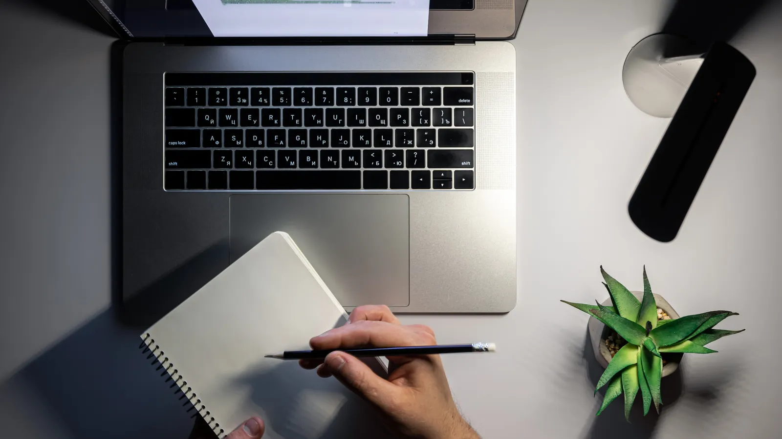 A laptop and a notebook with a hand-written migration plan on a desk