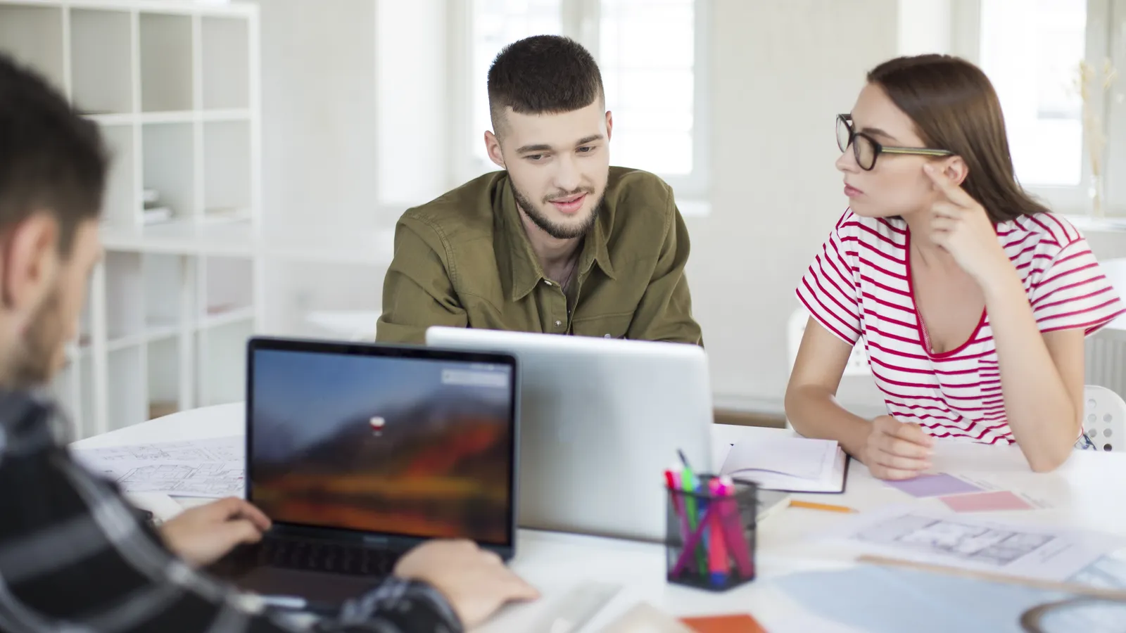 A product team discussing their website pages around a laptop